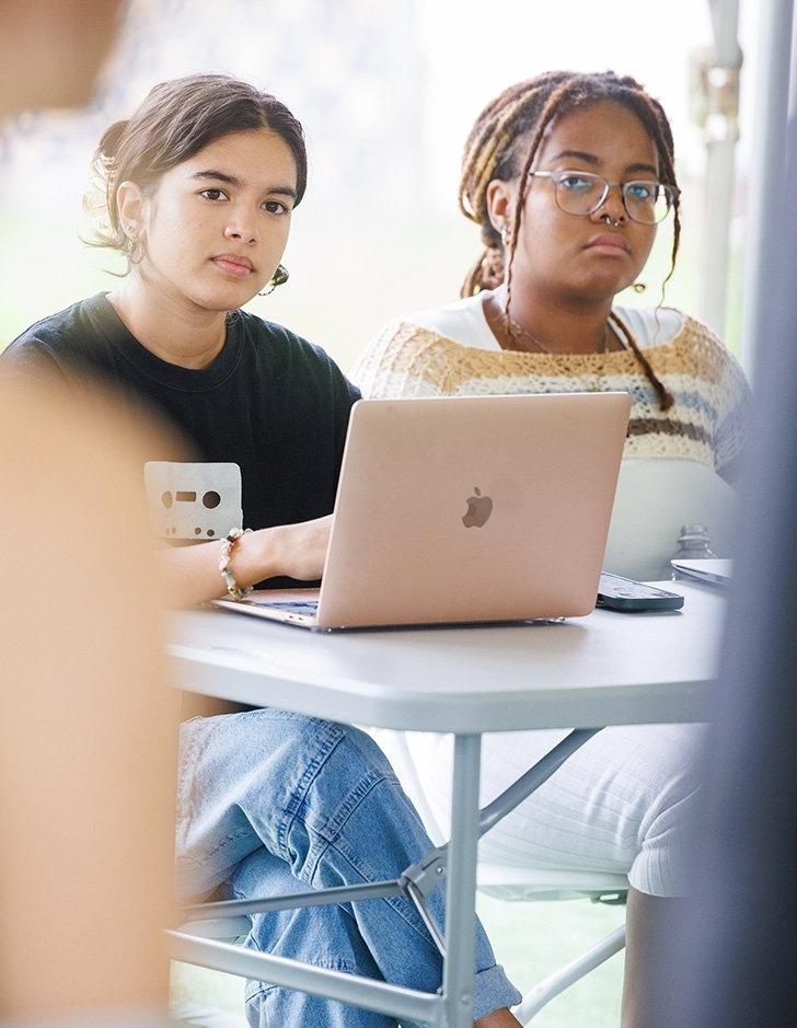 two students listen to another student speak in class